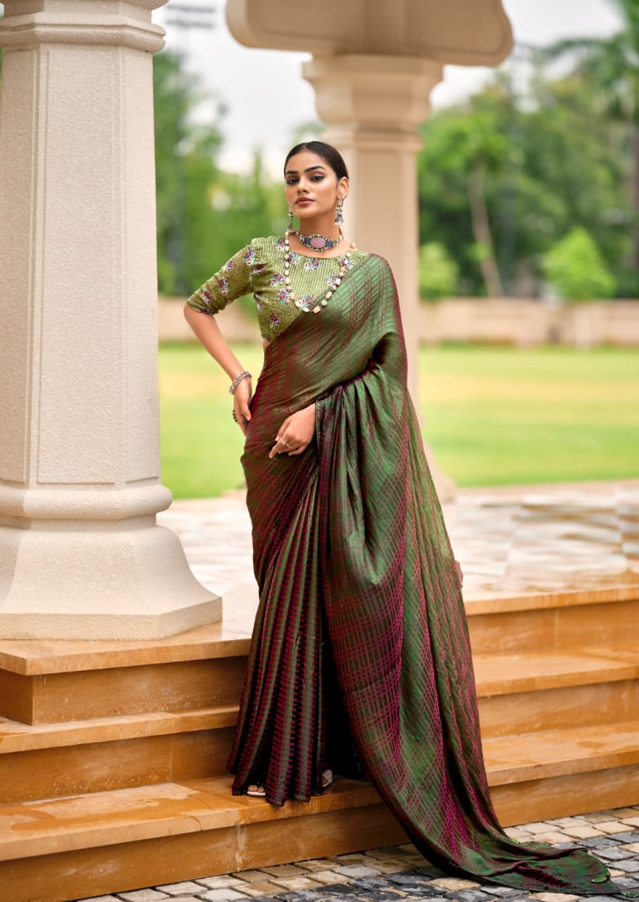 Woman in a green and brown saree standing outdoors near stone columns.