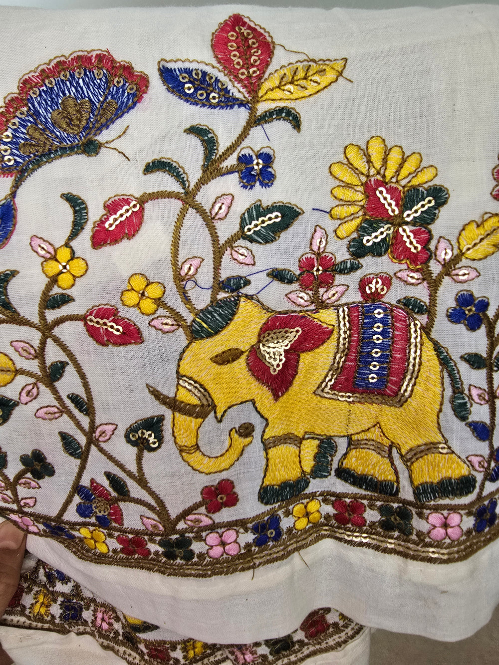 Close-up of a piece of fabric with intricate embroidery featuring butterflies and flowers.