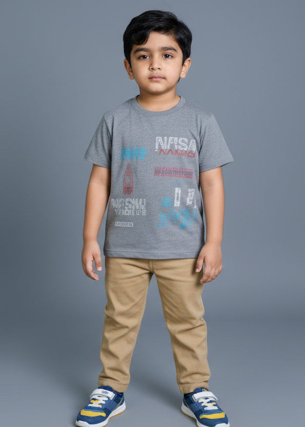 Child wearing a gray t-shirt with text and beige pants on a plain background