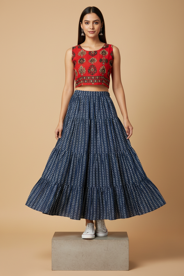 Woman wearing a red top with intricate patterns and a blue patterned skirt on a beige background