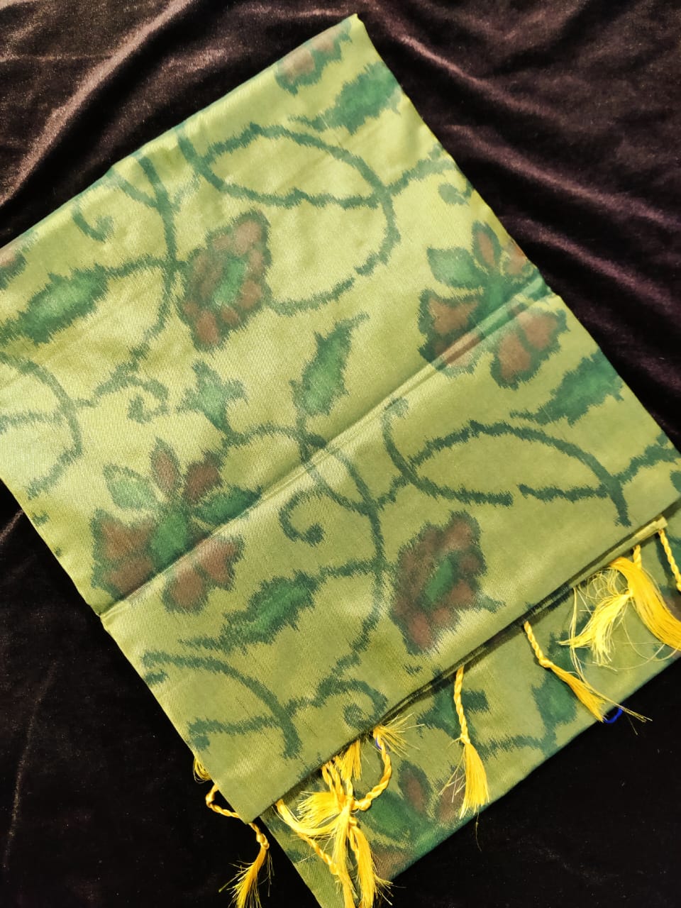 Green fabric with floral patterns on a dark background