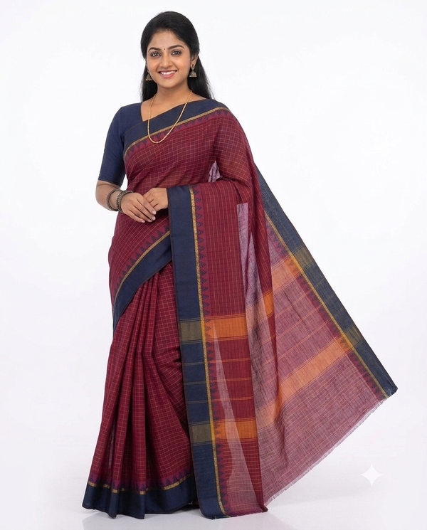 A woman modeling a dark red and navy blue checkered saree with orange and yellow striped accents on the pallu, paired with a navy blue blouse, against a plain white background.