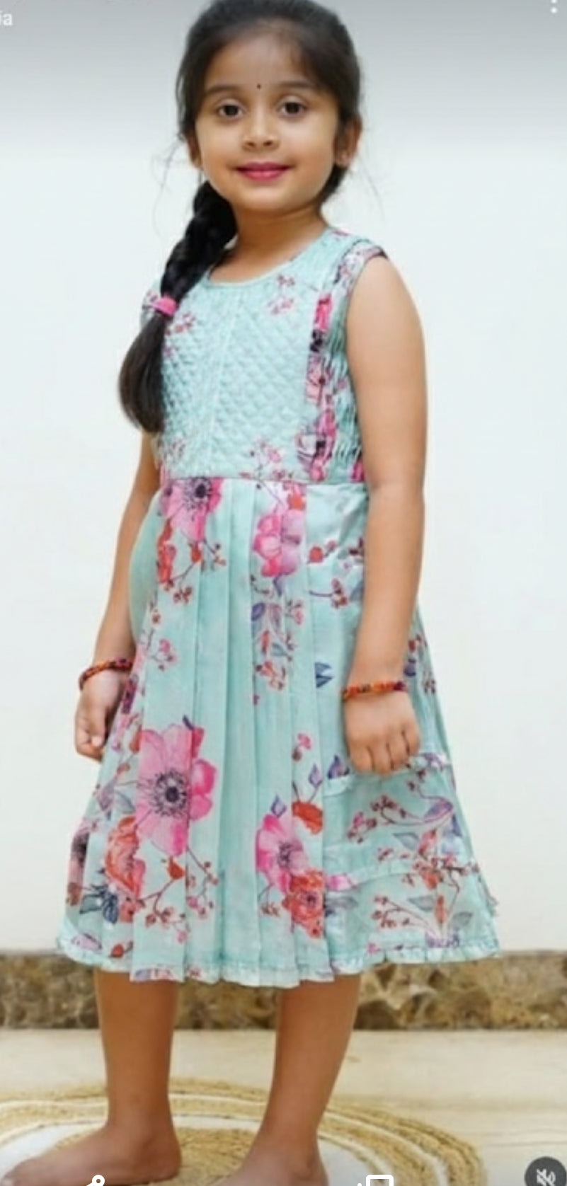 Young girl wearing a light blue floral dress against a plain background