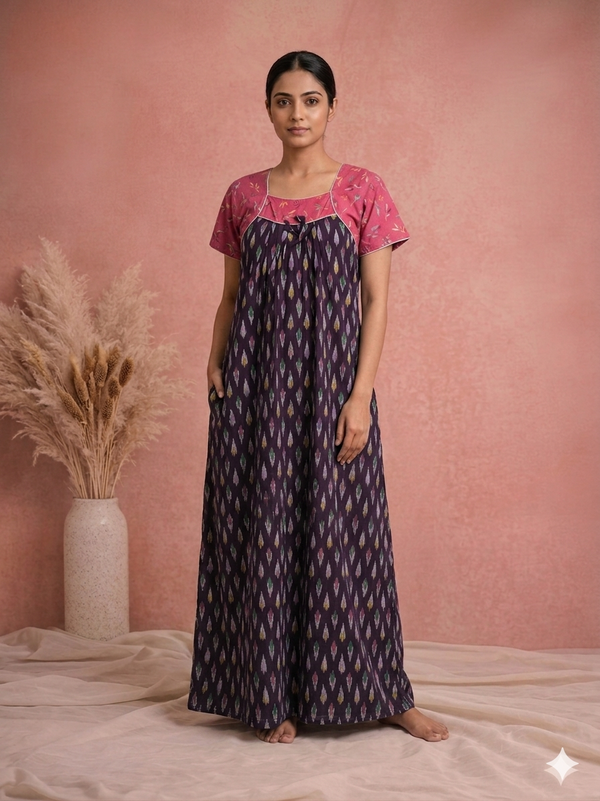 Woman wearing a pink top and purple patterned dress against a pink background
