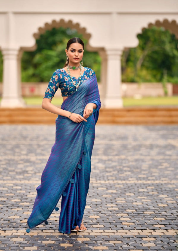 Woman in a blue saree with a floral blouse standing on a stone path.